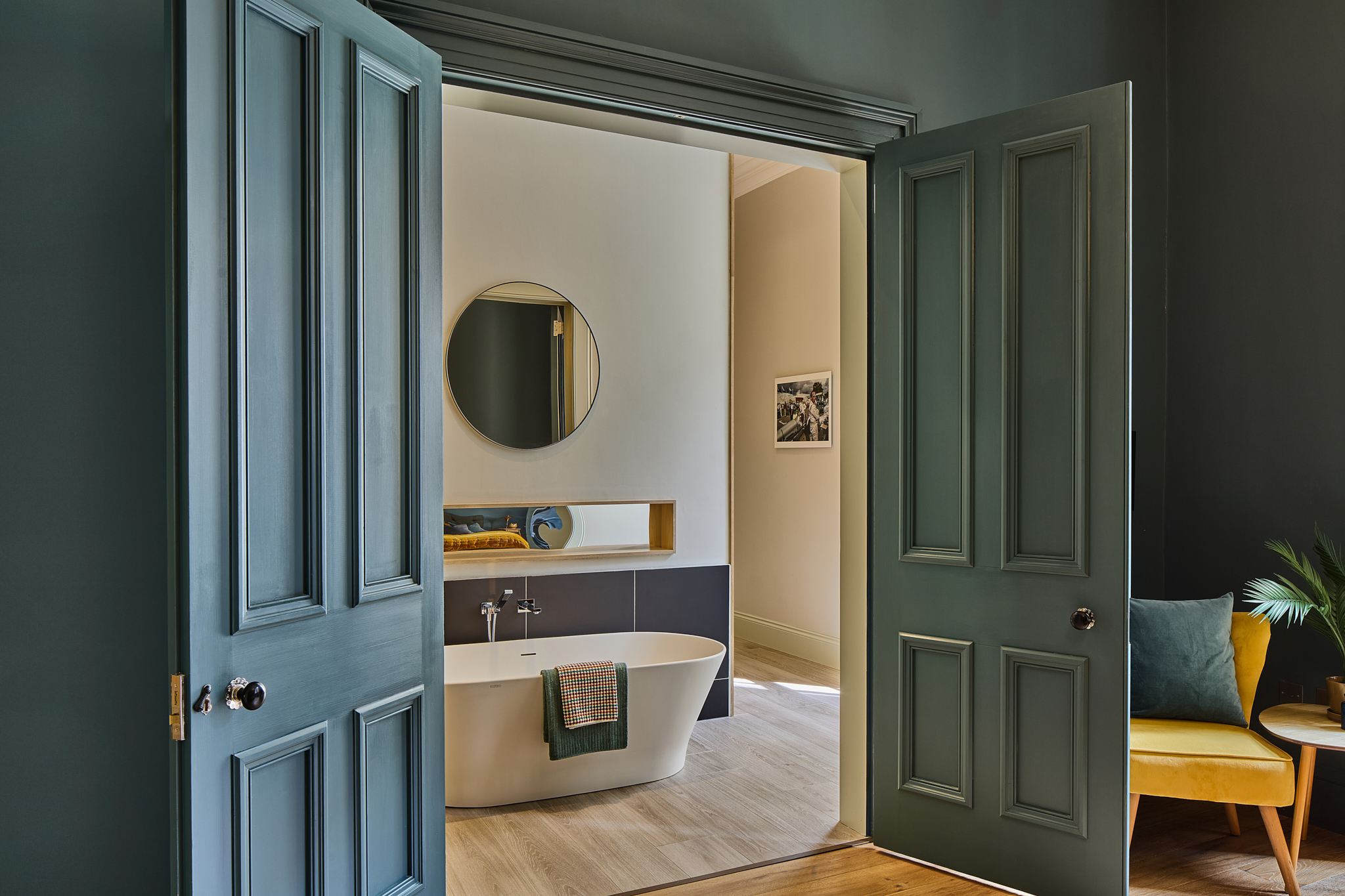 Green-panelled room with a round mirror