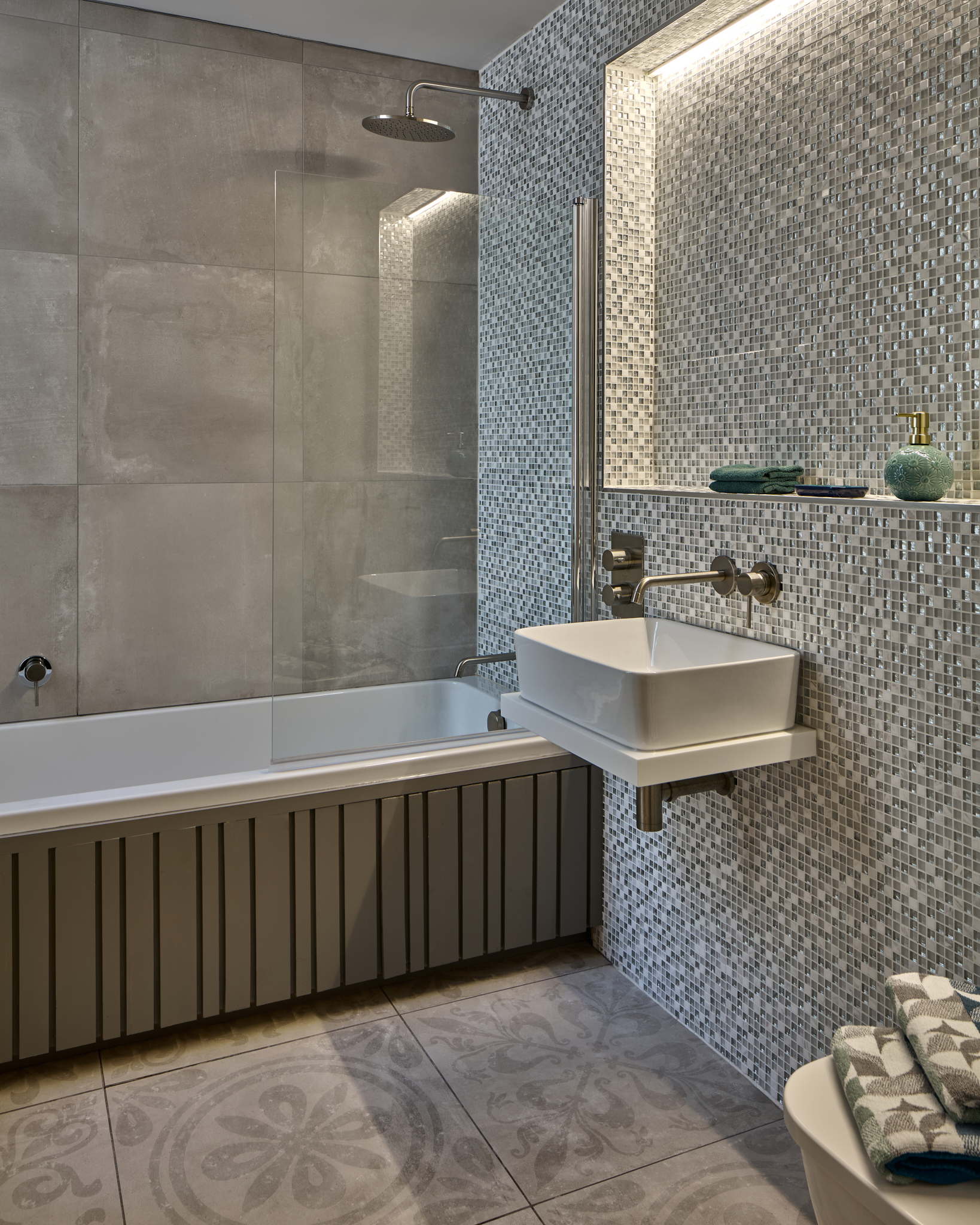 Bath set against mosaic tiling with a panelled radiator
